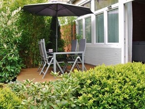 An outdoor patio with a table and chairs, surrounded by greenery and a covered area. - 5091 - Sauna and 4 bedrooms - 5091 - 4 bedrooms and infrared sauna (Dahme)
