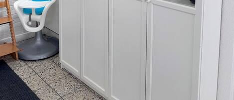 Un armario blanco con puertas de cristal que contiene diferentes utensilios de cocina.