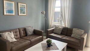 A living room with two brown leather sofas, a white coffee table, and two framed pictures on the wall.