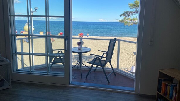 A room with a large sliding glass door leading to a balcony with a view of the beach and ocean. - 4100 - Beach house 25 - 4100 - Beach house - An der Strandpromenade 25 (Dahme)