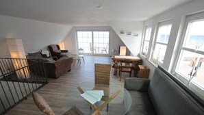 A spacious living area with a glass table, wicker chairs, a sofa, and a piano. - 4100 - Beach house 25 - 4100 - Beach house - An der Strandpromenade 25 (Dahme)