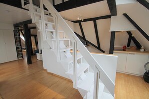 A modern interior with a white staircase, wooden flooring, and exposed black beams.