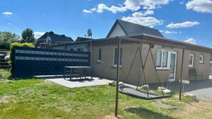 Une propriété résidentielle dotée d’une terrasse, d’une balançoire et d’une maison en briques.