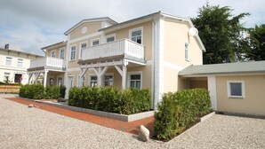 A two-story building with a balcony, a gravel driveway, and a small garden area. - Beach shell - Alte Da(h)me - New 1024 - Beach shell - Die Alte Dahme - New (Dahme)