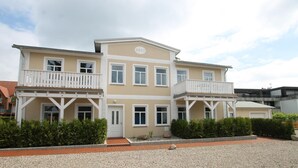 A two-story building with a balcony on the ground floor and a door with a small porch. - Beach shell - Alte Da(h)me - New 1024 - Beach shell - Die Alte Dahme - New (Dahme)