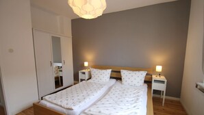 Une chambre à coucher comprenant un lit, deux tables de chevet, une commode, un miroir et une armoire.