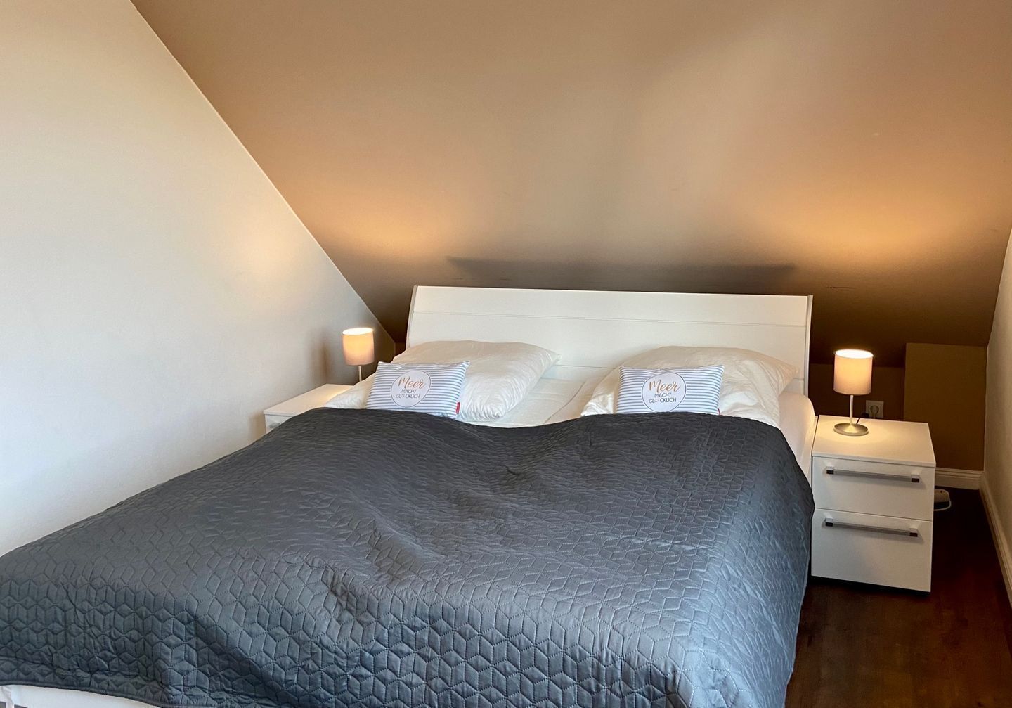 A bedroom with a bed, two bedside tables, and a nightstand.