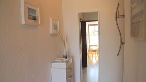 A hallway with a white cabinet, a mirror, and a door leading to a dining area.