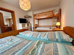 Ein Zimmer mit Etagenbetten, einem Fernseher, einer Lampe und einem Schrank.