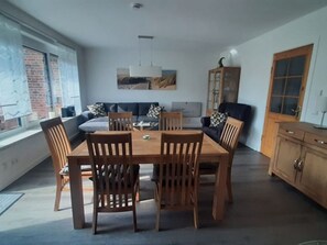 Un área de comedor con una mesa y sillas de madera, un sofá, un armario y un cuadro en la pared.