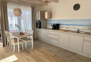 Una cucina moderna con mobili bianchi, un piano di lavoro in legno e un murale raffigurante una spiaggia.