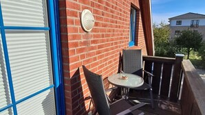 Un patio con tavolo e sedie, una finestra con persiane e un muro in mattoni.