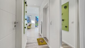 A modern hallway with white walls, a wooden floor, and a yellow welcome mat. - 1003 - Lütt Wulkjes - Lütt Wulkjes - Nordic charm (Dahme)