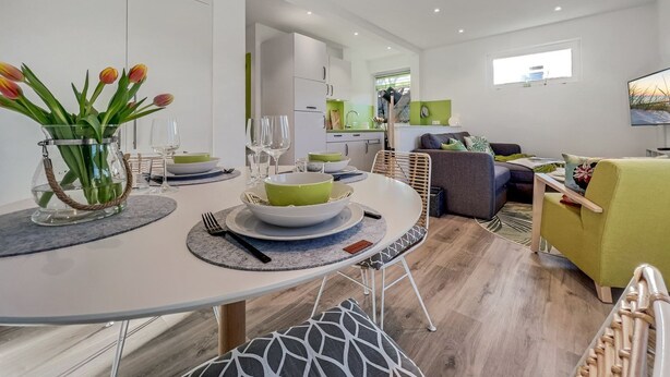 A modern dining area with a round table, chairs, and a vase of tulips. - 1003 - Lütt Wulkjes - Lütt Wulkjes - Nordic charm (Dahme)
