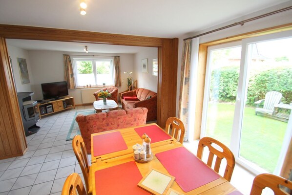 A dining area with a wooden table, chairs, and a television in the background.