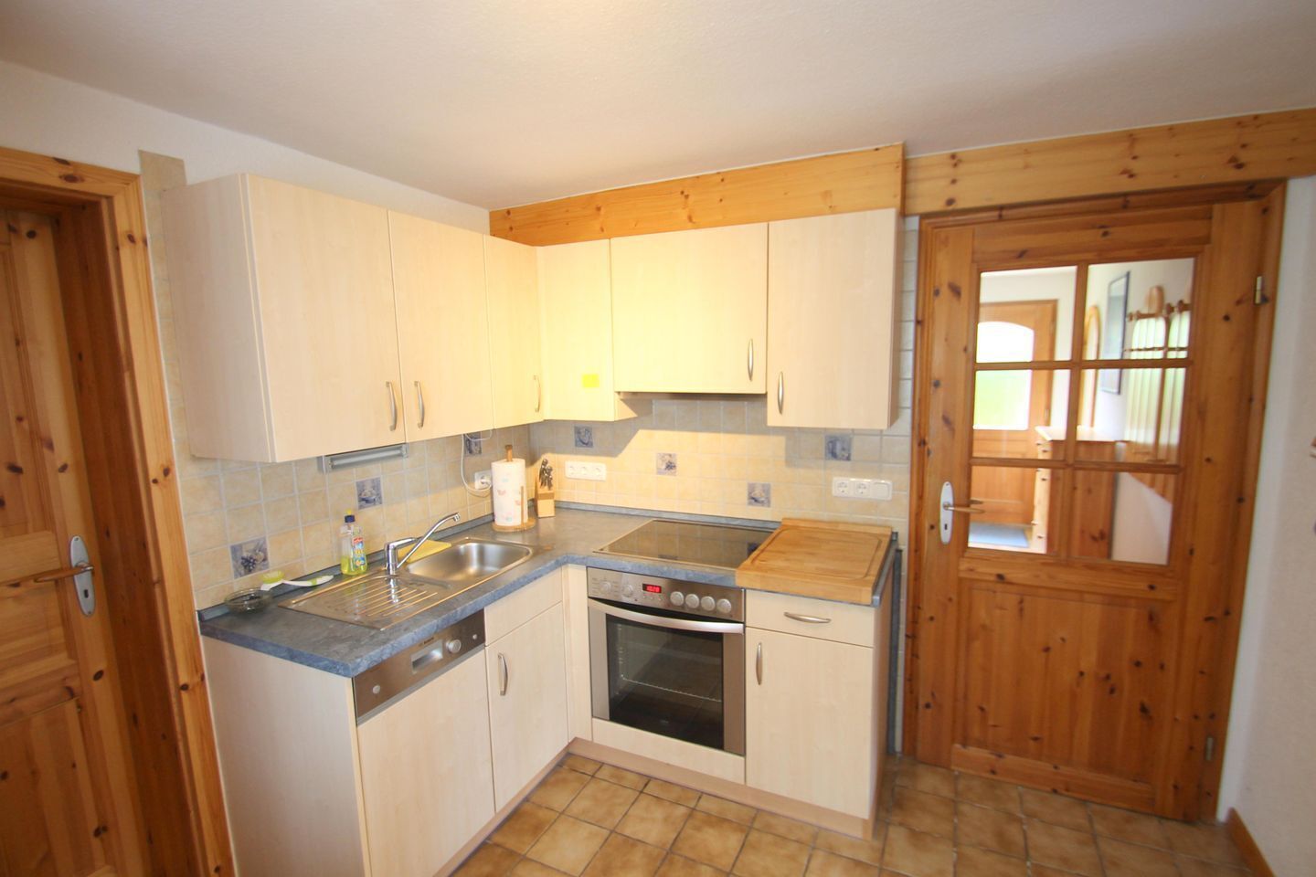 A compact kitchen with wooden cabinets, a built-in oven, and a sink.