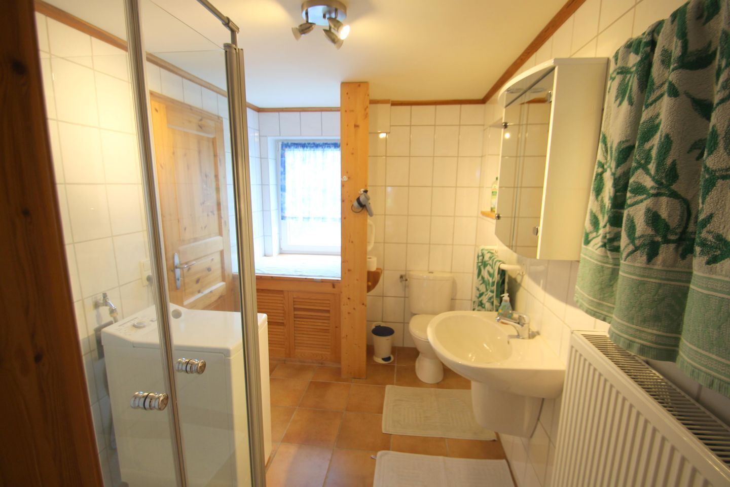 Une salle de bain avec une douche, des toilettes, un lavabo et une fenêtre.