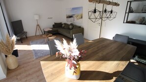 Een moderne woonkamer met een houten eettafel, een bank en een lamp.