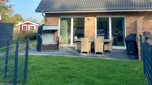 Een herenhuis met een bakstenen gevel, een pannendak en een overdekte patio met tuinmeubilair.