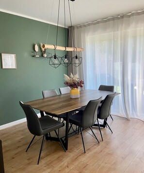 Ein Essbereich mit einem Holztisch, schwarzen Stühlen und einer Pendelleuchte.