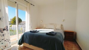 Een slaapkamer met een bed, nachtkastje en een raam met gordijnen.