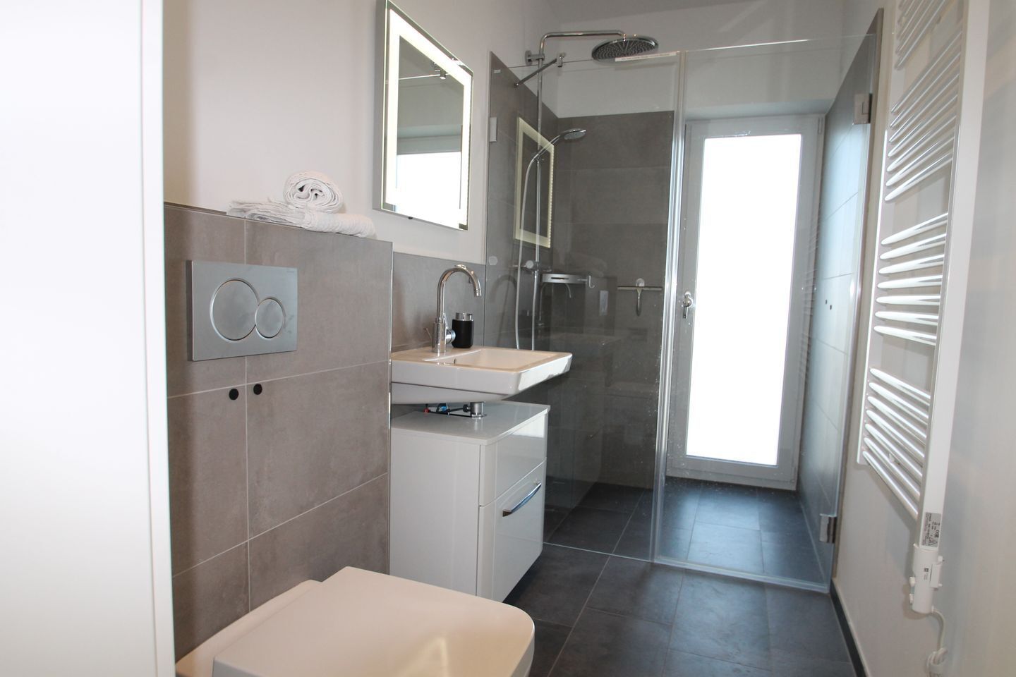 Ein modernes Badezimmer mit Dusche, Waschbecken und Toilette.