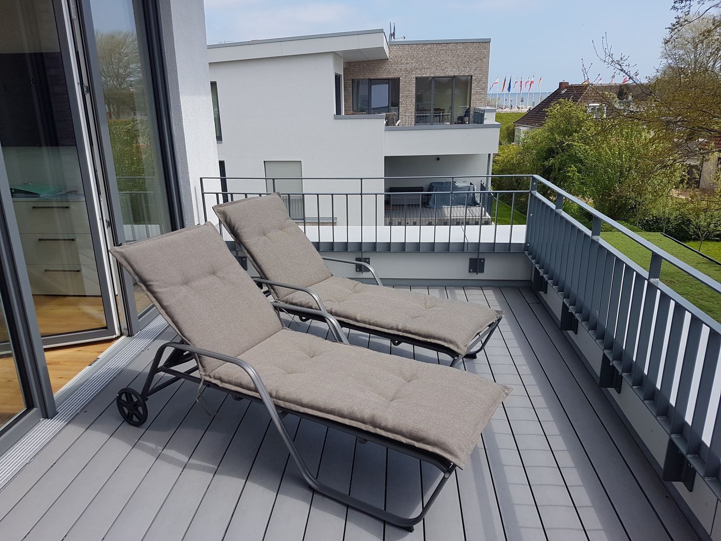 Ein Balkon mit zwei Liegestühlen und einer Glastür, die zu einem Raum führt.
