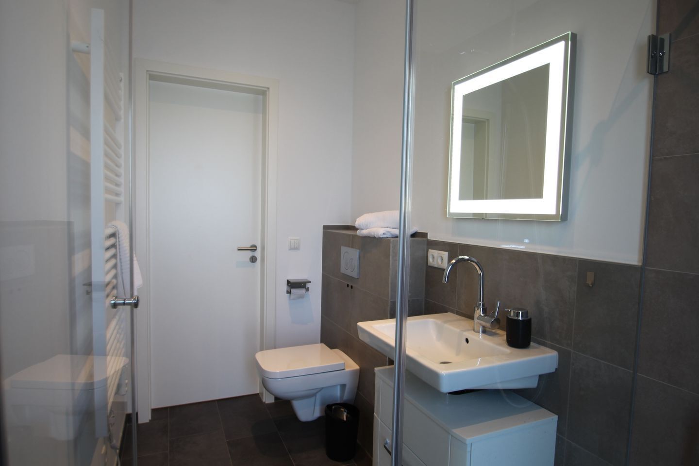 Un baño moderno con inodoro, lavamanos y cabina de ducha de vidrio.