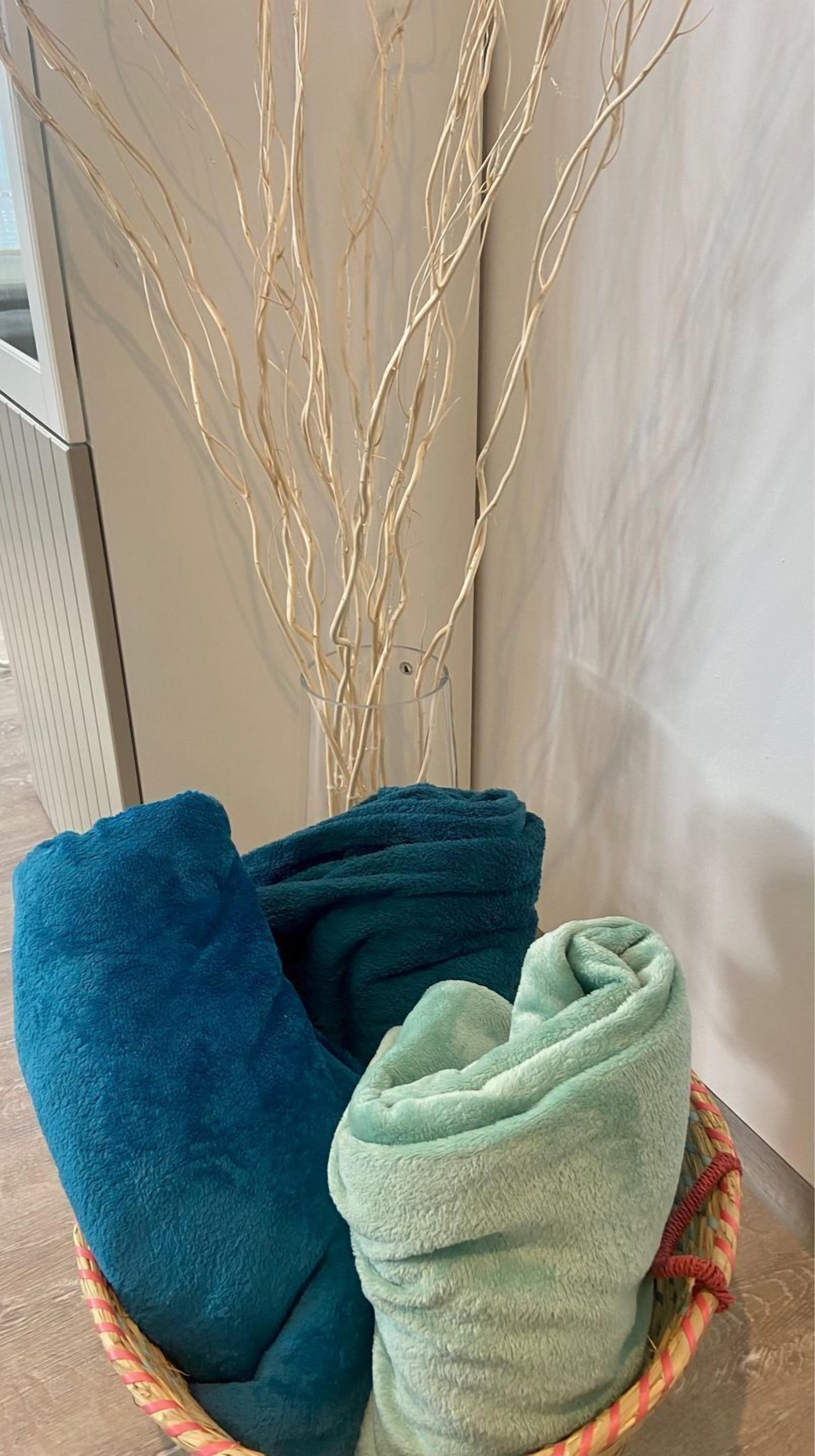 A basket with folded towels in blue and green colors.