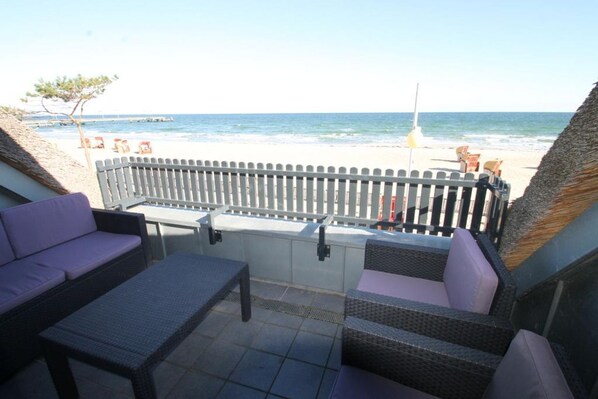 Un patio con mobiliario de mimbre y vista a la playa.