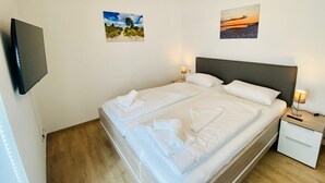 A double bed with white linens, a bedside table with a lamp, and two framed pictures on the wall. - 2803 - Strandliebe - Apartment Strandliebe (Dahme)