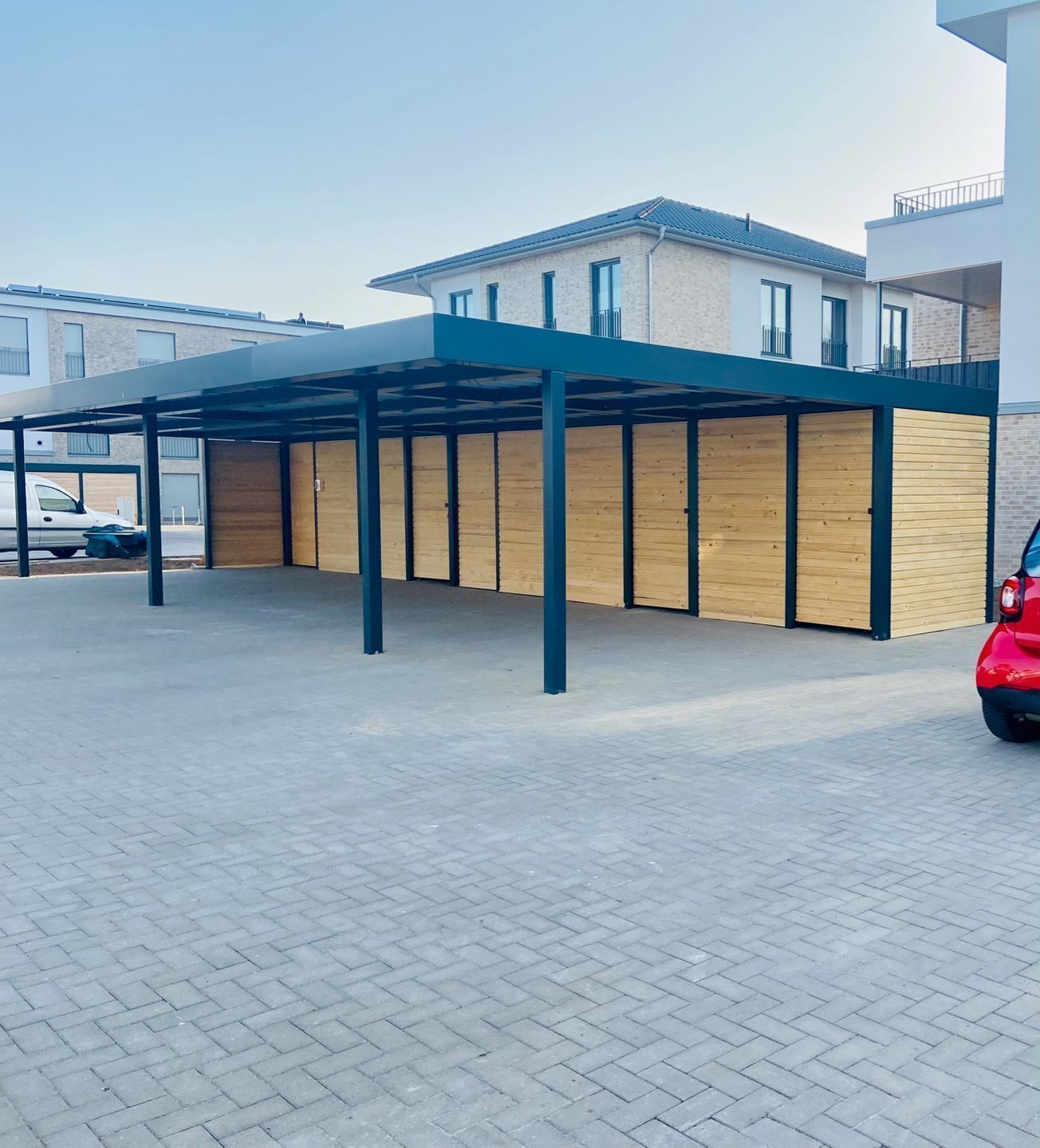 Ein überdachter Parkbereich mit einem modernen Gebäude im Hintergrund.