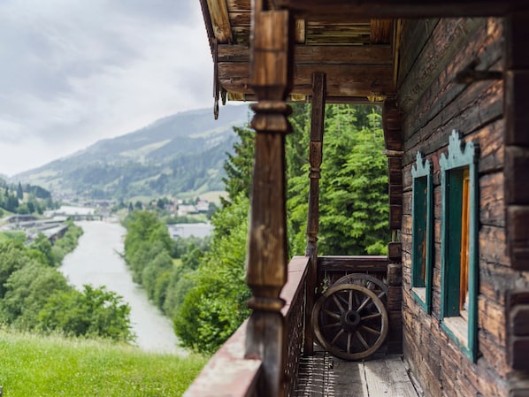 Une cabane en bois dotée d’un balcon donnant sur une rivière et des montagnes.