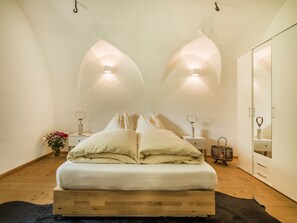 Une chambre à coucher avec un lit, deux tables de chevet, une commode, un miroir et un plancher en bois.