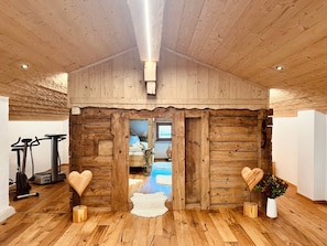 Un intérieur en bois avec un luminaire au plafond, des murs en bois, un banc en forme de cœur et un tapis de course.