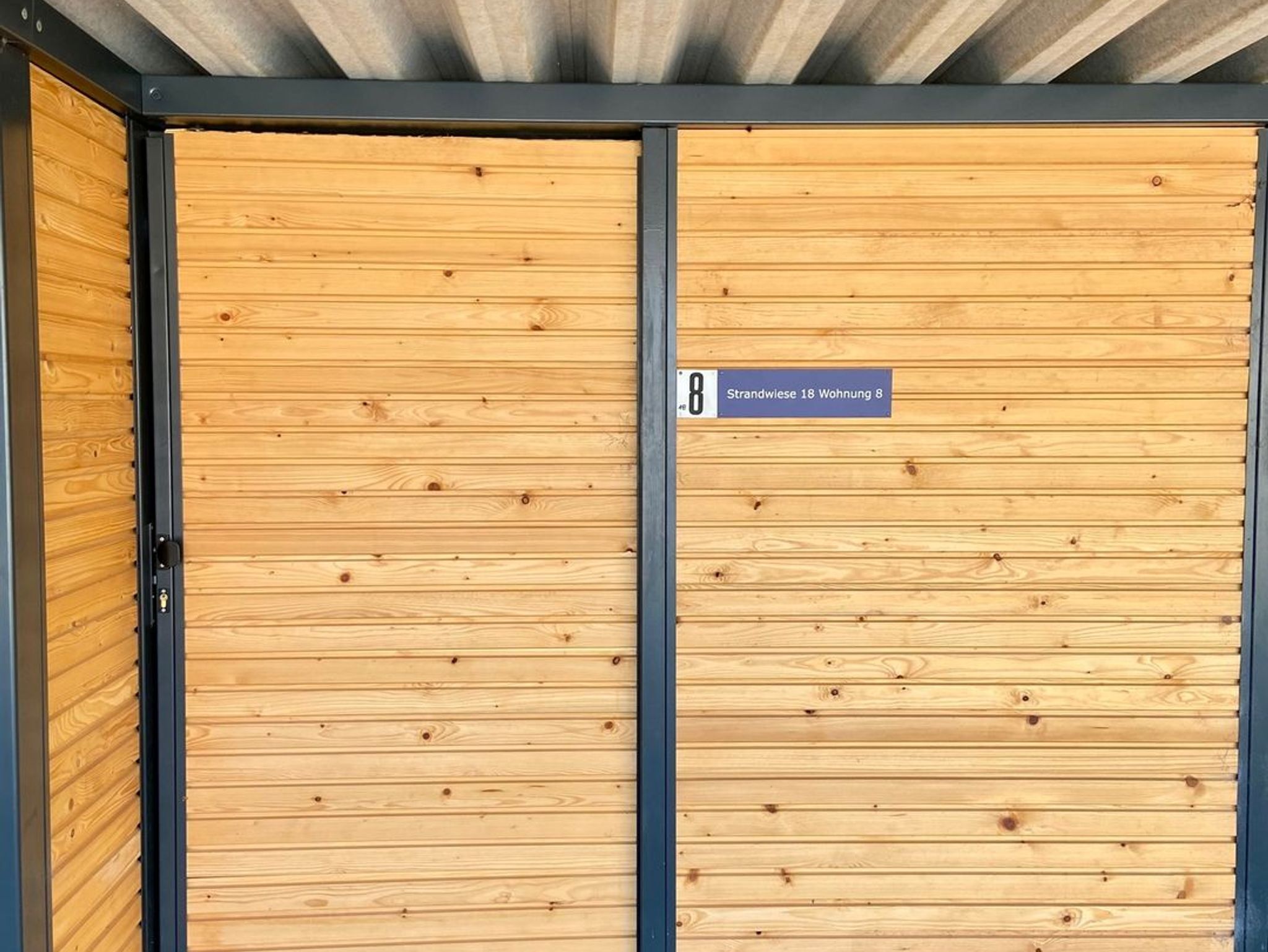 A wooden door with a metal frame and a sign indicating room number 8.
