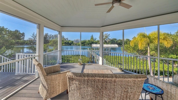 A covered outdoor area with wicker furniture, a ceiling fan, and a view of a lake and dock. - Pool home on Bocilla Lagoon (Placida)