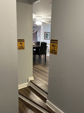 Walk down the hallway to a dining area with a table and chairs, featuring a ceiling fan above.