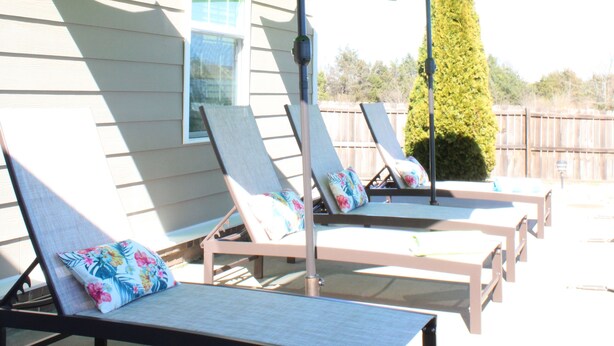 Un espace aménagé au bord de la piscine, avec des chaises longues et un parasol vert.