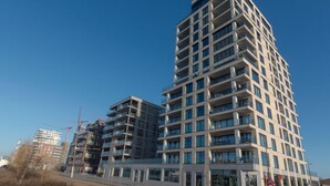 Een modern meerlaags gebouw met een gelijkmatige gevel, grote ramen en balkons.