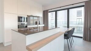 Een moderne keuken met een centraal eiland, roestvrijstalen apparatuur en een groot raam met uitzicht op de stad.