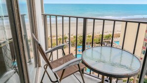Ein Balkon mit Blick auf den Strand, einem runden Tisch und einem Stuhl.