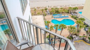 Ein Poolbereich mit Liegestühlen, Palmen und Blick auf den Strand.