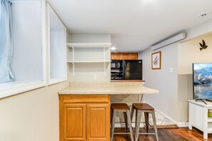 Compact kitchen area with countertop and cabinetry, featuring a refrigerator, microwave, and seating for two.
