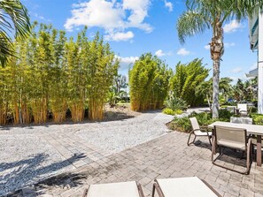 Un espace patio agrémenté d’un chemin de gravier, de plantes en bambou et de mobilier d’extérieur.