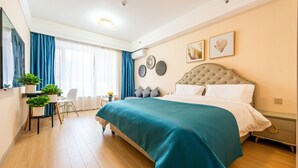 Een moderne slaapkamer met een groot bed, een bureau met stoel, en een raam met gordijnen.