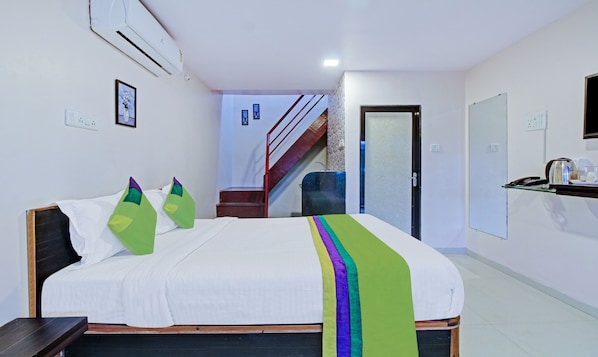 Ein Hotelzimmer mit einem Bett, einem Schreibtisch, einem Sessel, einer Treppe und einer Klimaanlage.
