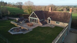 A large stone house with a sloped roof, a patio with outdoor furniture, and a well-maintained lawn. - Apple Loft -  Beautiful Somerset cottage, sleeps 13 guests  in 6 bedrooms (Ilminster)