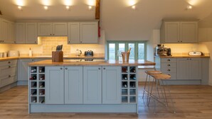 A spacious kitchen with a central island, wooden countertops, and a wine rack. - Apple Loft -  Beautiful Somerset cottage, sleeps 13 guests  in 6 bedrooms (Ilminster)