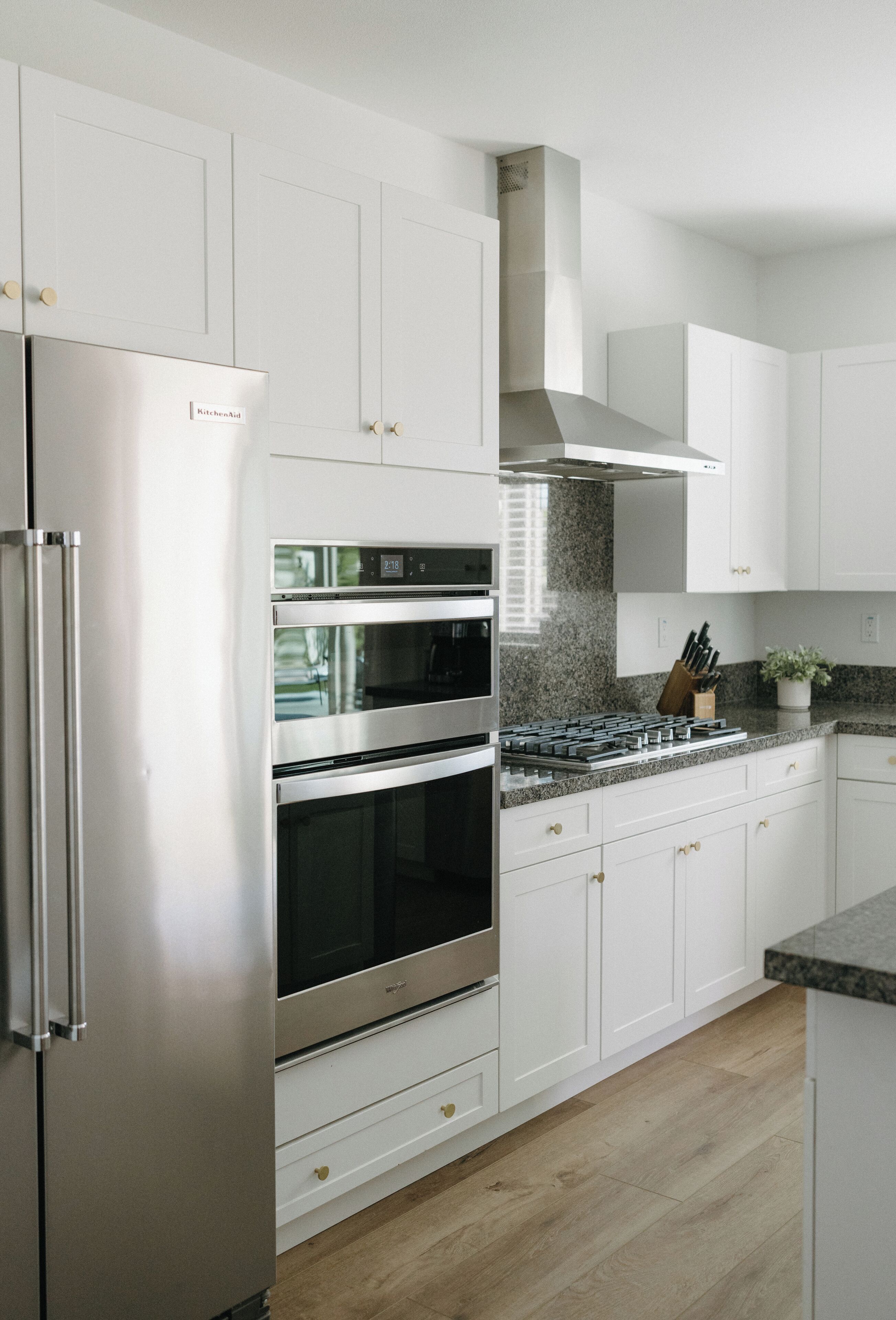 A modern kitchen with white cabinetry, stainless steel appliances, and a granite countertop.
